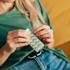 Kobieta trzyma opakowanie tabletek. Pytanie, kiedy brać tabletki na nadciśnienie, jest kluczowe dla zdrowia.