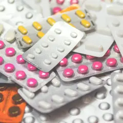 Stos leków w blistrach, w tym różowe i żółte tabletki, które mogą być lekami na demencję.
