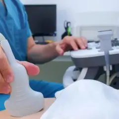 Lekarz wykonuje badanie USG, aby zbadać trzustkę pacjenta. Aparatura i sonda są widoczne.