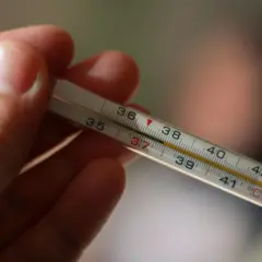 Dłoń trzyma termometr, na którym widać wynik 37°C. To normalna temperatura pod językiem.