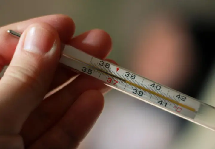 Dłoń trzyma termometr, na którym widać wynik 37°C. To normalna temperatura pod językiem.
