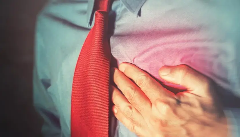 Mężczyzna trzyma się za klatkę piersiową, odczuwając ból. Może to być jeden z **diuresin skutki uboczne**.