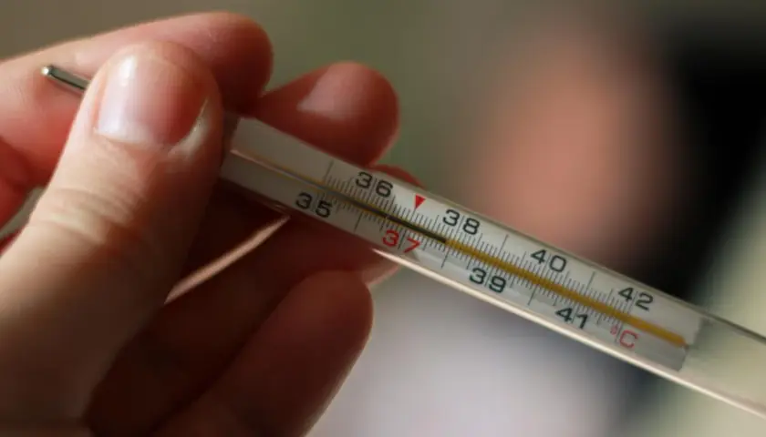 Dłoń trzyma termometr, na którym widać wynik 37°C. To normalna temperatura pod językiem.
