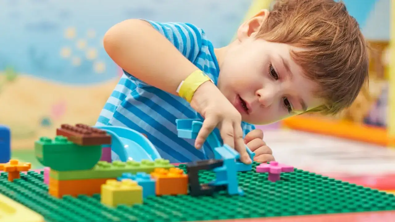 Dziecko z uśmiechem bawi się klockami, pochłonięte zabawą